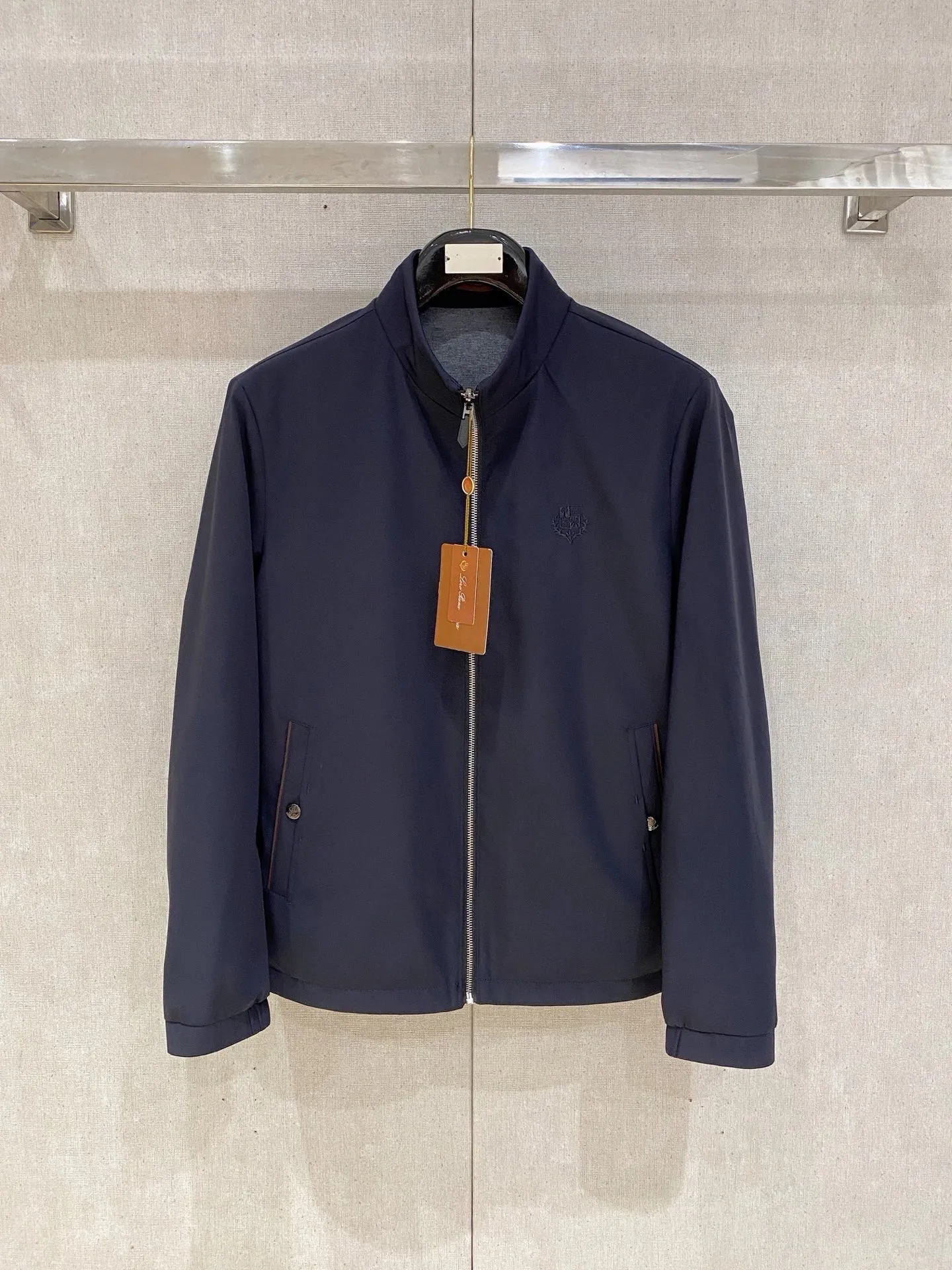 Loro Piana Reversible Stand Collar Jacket Fabric: The front is made of high-elastic anti-wrinkle functional windproof fabric. The fabric surface is smooth and smooth. It is slightly water-repellent, anti-fouling and easy to care for. It is not easy to wrinkle and deform. It can be worn in spring, autumn and early winter. The back is made of worsted wool knitted fabric, which is soft and skin-friendly, breathable and constant temperature. One pair of fabrics creates two styles of wear. It is the iconic Italian old-money style commuting fabric. Design highlights: Double-wearable and dual-style design, the functional side is smart and business-like, and the knitted side is soft and casual, allowing you to switch between two atmospheres when wearing one set; the front left chest is embellished with the same color dark pattern embroidered brand badge, which is low-key and restrained, unobtrusive and highlights the high-end texture; The side of the pocket is spliced with Brown Genuine Leather trim strips, with metal snaps, full of light and luxurious details; The knitted side neckline is matched with Navy Blue contrasting brown and yellow striped ribs, giving the brand a subtle and advanced sense of recognition; The custom-made metal zipper is smooth and durable, the body wiring is neat and precise, and the workmanship is exquisite. Style and structure: Improved high stand-up collar tailoring, fits the neck without snags, optimizing the head-shoulder ratio; lightweight thin quilted filling, keeping warm without bulk, and zero weight on the upper body; slightly loose straight cut, to accommodate all body shapes, and can be worn with shirts, polo, and thin knitted fabrics without restraint; symmetrical welt pockets with metal snaps to store belongings securely and prevent them from slipping; ribbed cuffs, windproof and temperature-locking, and modified arm lines. Style positioning: Premium is suitable for light business commuting, urban leisure, and short-distance travel. It is minimalist, low-key, and elegant. Mature men need jackets all year round. Color: Black, Navy Blue (unified Gray knitted surface on the reverse side) Sizes: M-4XL